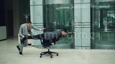 玩的商人们在办公室大厅里的骑椅上玩得很开心，在摇椅上玩<strong>赛车游戏</strong>
